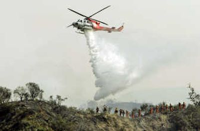 A firefighting helicopter makes a drop on a slope Sunday in Sierra Madre, Calif. Associated Press
(Associated Press / The Spokesman-Review)