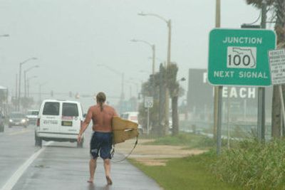 
A surfer carries his board alongside Route A1A in Flagler Beach, Fla., Friday, after trying to ride huge waves pounding the shore. Tropical Storm Ophelia regained hurricane strength and could threaten the gulf coast, forecasters said Friday.
 (Associated Press / The Spokesman-Review)