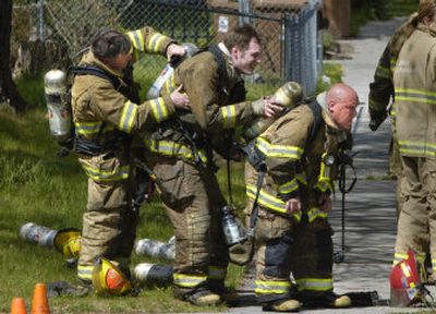 
Spokane firefighters John Gilbert, Lee Hammons and Jimmy Bowen, from left, help one another change air bottles at a house fire at 821 W. Dalton Ave. on Tuesday. 
 (Photos by Dan Pelle / The Spokesman-Review)