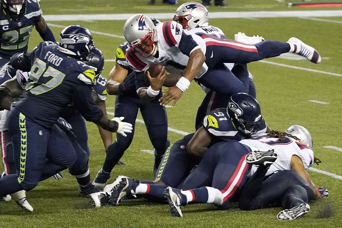 New England Patriots quarterback Cam Newton dives with the ball but is stopped short of the goal line by Seahawks defenders Delano Hill, bottom, and L.J. Collier as the clock runs out Sunday night in Seattle, preserving the Seahawks’ 35-30 victory.  (Elaine Thompson)