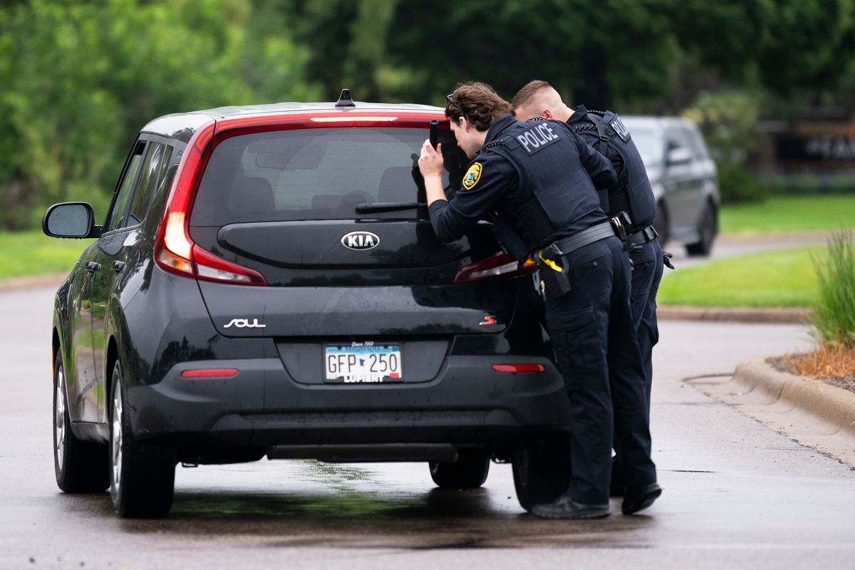 Top: Brooklyn Park police officers search a vehicle entering a neighborhood on Saturday in Brooklyn Park, Minn. Above: Vance Boelter’s roommate, who declined to give his name, speaks with a Minneapolis police officer outside his home on Saturday in Minneapolis following a raid of the residence by law enforcement. Boelter is a suspect in the shooting of two Democratic-Farmer-Labor lawmakers. (Stephen Maturen)