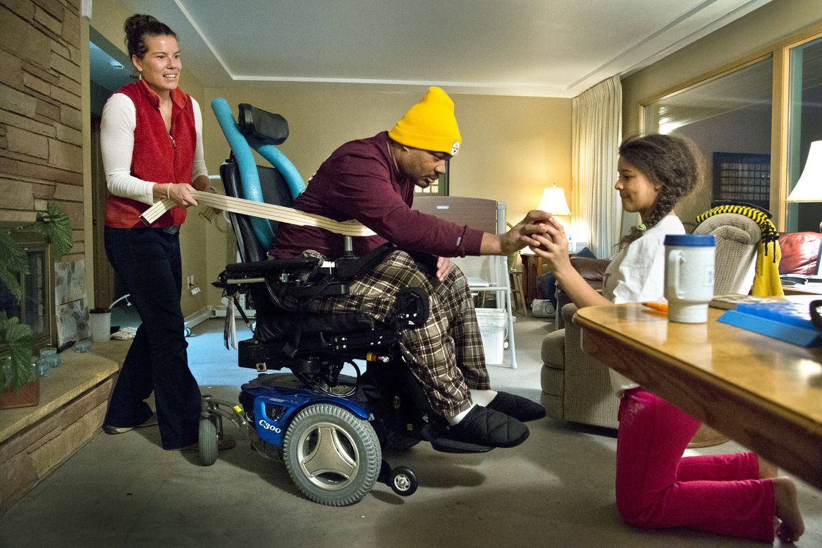 Al Palm works on his balance and strength, with the help of occupational therapist Emily Querna, left, and his daughter Joelle, on Dec. 2 at his home in northwest Spokane. (Dan Pelle)