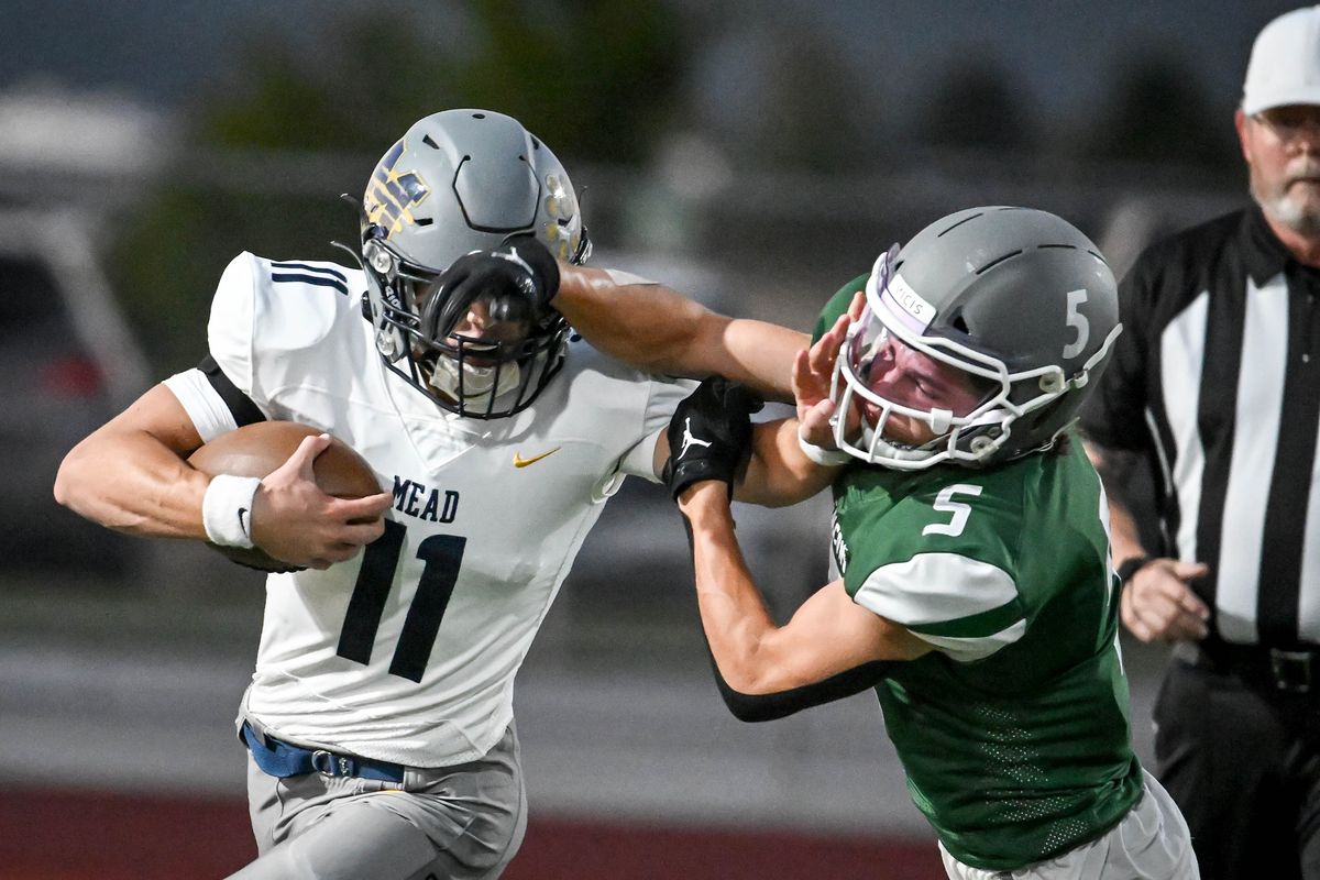 On a quarterback keeper, Mead quarterback Jaeland Leman (11) pushes off of Ridgeline defensive back Brayden Allen (5) during a high school football game, Friday, Sept. 15, 2023, at Ridgeline High School in Liberty Lake.  (Colin Mulvany/The Spokesman-Review)