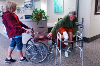 Thomas Nerison, who was attacked by a grizzly bear Sunday, gets into a wheelchair pushed by his wife, Doreen,   on Tuesday in Kalispell.  (Associated Press / The Spokesman-Review)