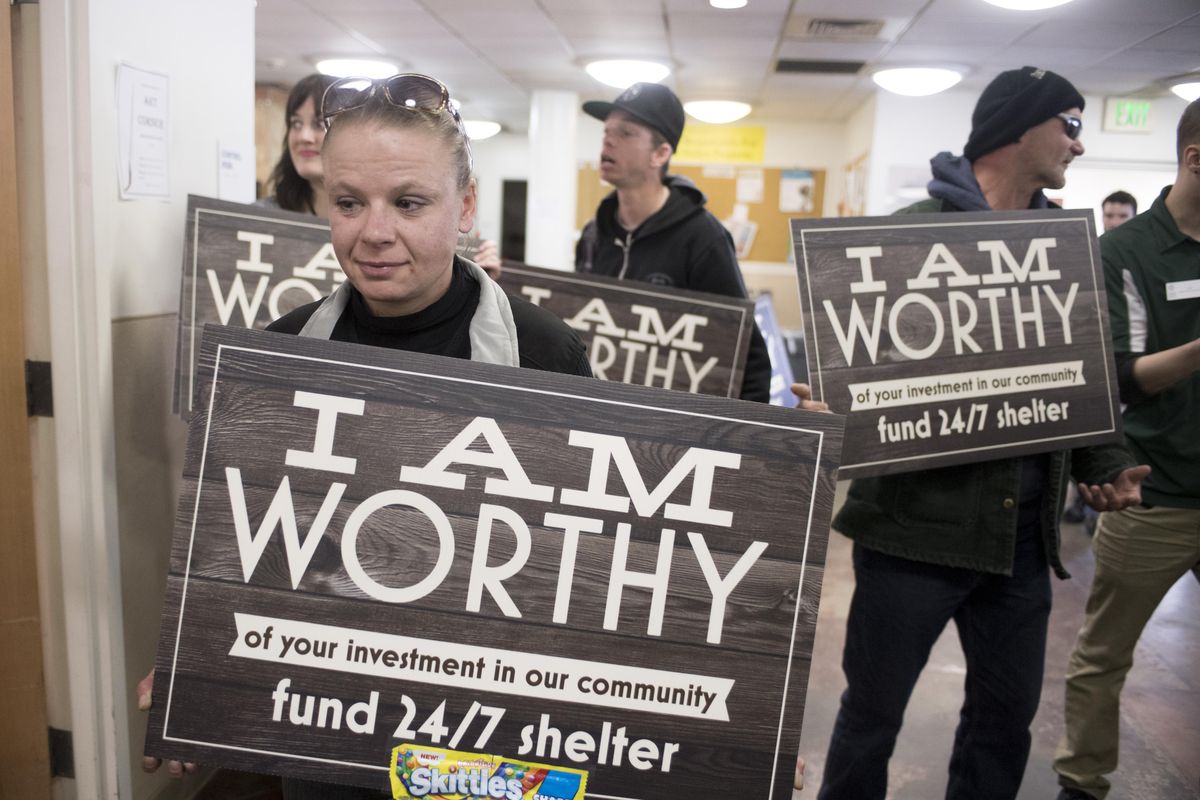 Trish Raddas, who has used services at the House of Charity shelter in downtown Spokane occasionally, holds a sign made to encourage city funding for the shelter at a press conference, Thursday, April 13, 2017, where HOC officials pleaded with the city for funding as a shortfall looms in May. (Jesse Tinsley / The Spokesman-Review)