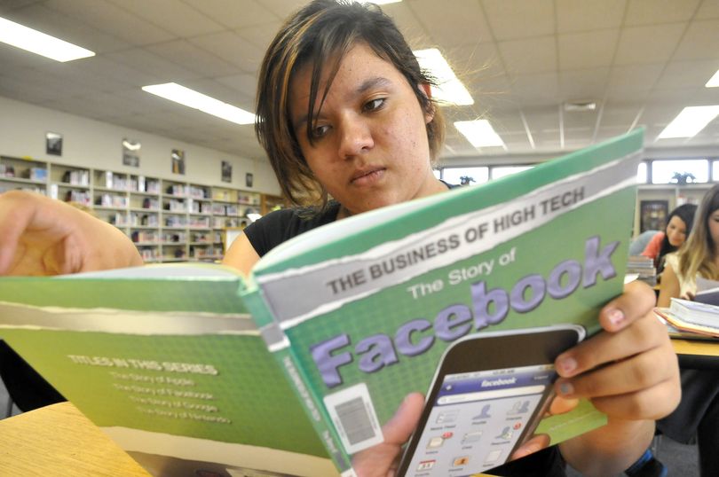 Ashlee Zack, 13, thumbs through a book about Facebook at North Pines Middle School library.