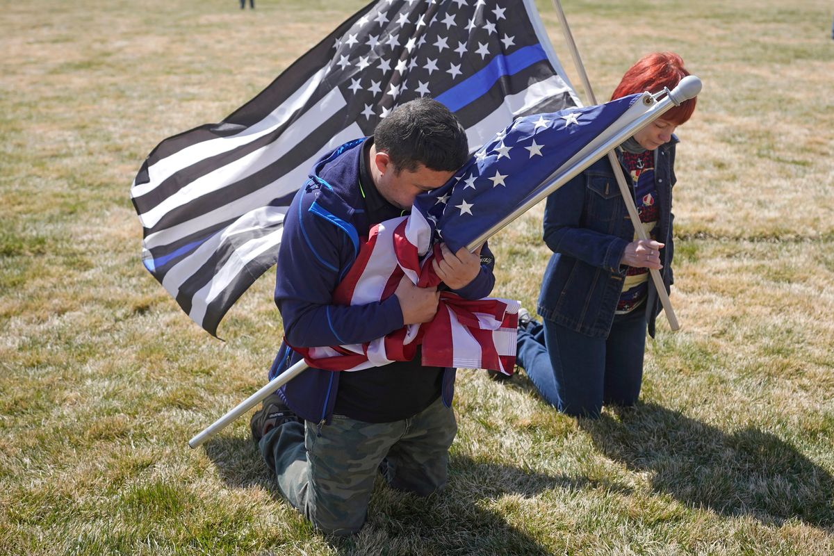 Marius Annandale, left, kneels while praying during a Second Amendment gun rights rally at the Utah State Capitol on March 27, 2021, in Salt Lake City.  (Rick Bowmer)