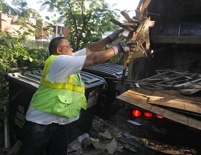 Ronny Purtty, who works as a trash collector for St. Louis’ bulk item crew, tosses scrap wood into a truck. Purtty used to drive an 18-wheeler delivering steel but was laid off last fall.  (Associated Press / The Spokesman-Review)