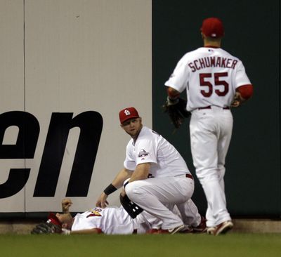 Chris Duncan and Skip Schumaker help teammate Rick Ankiel, who crashed into the outfield wall. (Associated Press / The Spokesman-Review)