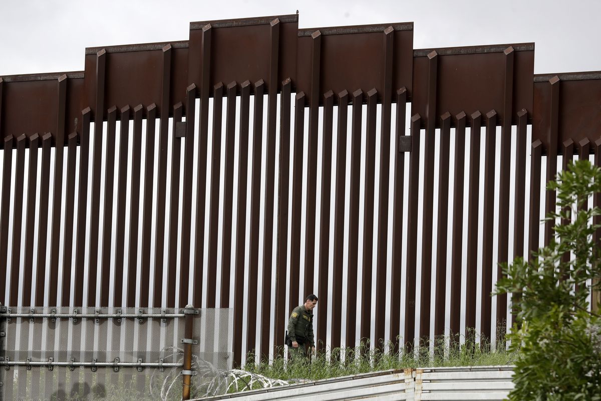 FILE - In this March 18, 2020, file photo, a Border Patrol agent walks along a border wall separating Tijuana, Mexico, from San Diego, in San Diego. U.S. authorities wield extraordinary power available in public health emergencies, like the coronavirus pandemic, to expel Mexicans and many Central Americans immediately to Mexico and waive immigration laws that include rights to seek asylum.  (Gregory Bull)