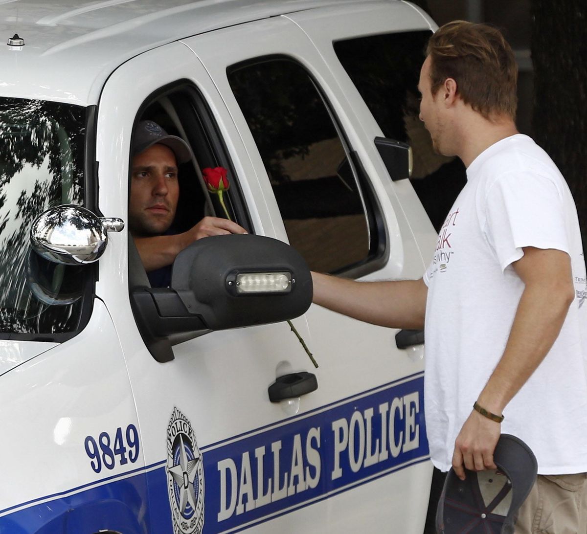 John Fife hands a police officer guarding Jack Evans Police Headquarters a rose in Dallas on Friday July 8, 2016. Snipers opened fire on police officers in the heart of Dallas during protests over two recent fatal police shootings of black men. (Nathan Hunsinger / Dallas Morning News via AP)