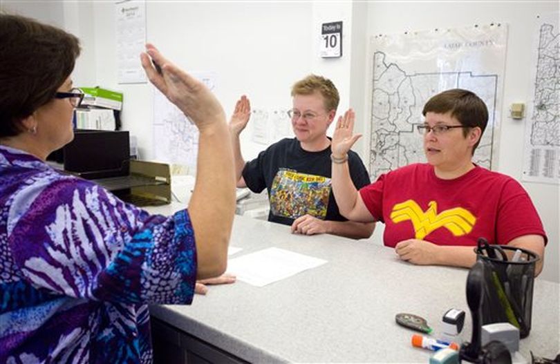 Katherine Sprague, center, and Tabitha Simmons, right, take an oath under the direction of Deputy Recorder Stacey Chapman while applying for their marriage license at the Latah County Courthouse in Moscow, Idaho, on Friday, Oct. 10, 2014. Sprague and Simmons were the first couple to be issued a same-sex marriage license in Latah County. (AP/Moscow-Pullman Daily News / Geoff Crimmins)