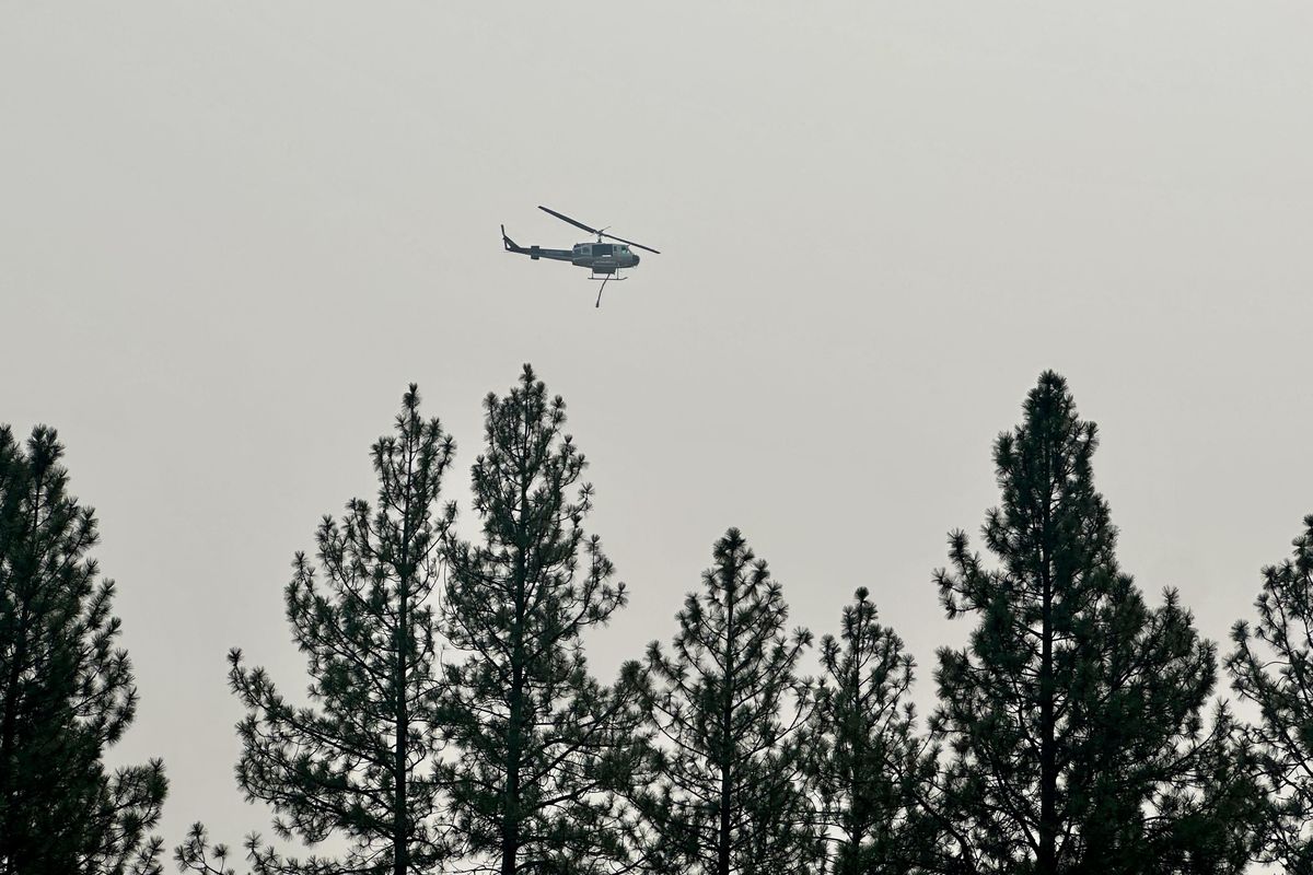 A helicopter drops water on a fire burning in the Latah Valley on Sunday afternoon. The 15-acre fire has prompted get-read-to-leave notices for residents west of U.S. Highway 195.  (Rob Curley/The Spokesman-Review)