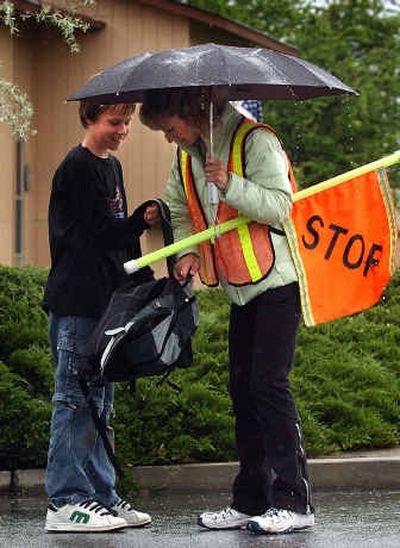 
Kevin Kelly, 11, hands his crossing guard mom, Lisa, his backpack so she can feel how heavy it is at Wellesley and Sunnyvale Drive in the Spokane Valley. 
 (Liz Kishimoto / The Spokesman-Review)