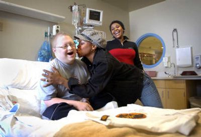 
Lion King cast member Shaullanda LaCombe kisses Robby Bartcher in his room at Sacred Heart Children's Hospital while fellow cast member Gugwana Dlamini watches during a visit Tuesday morning. LaCombe plays Shenzi the hyena and Dlamini plays Rafiki in 