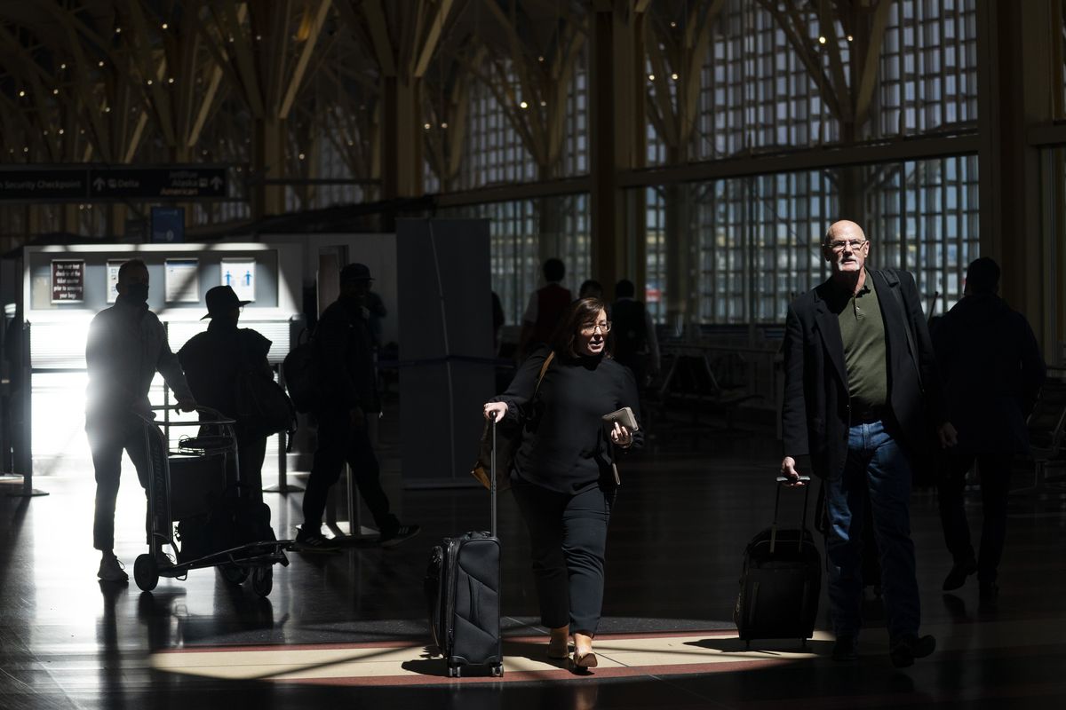 Passengers walk through the terminal at Ronald Reagan Washington National Airport, Tuesday, April 19, 2022, in Arlington, Va. A federal judge