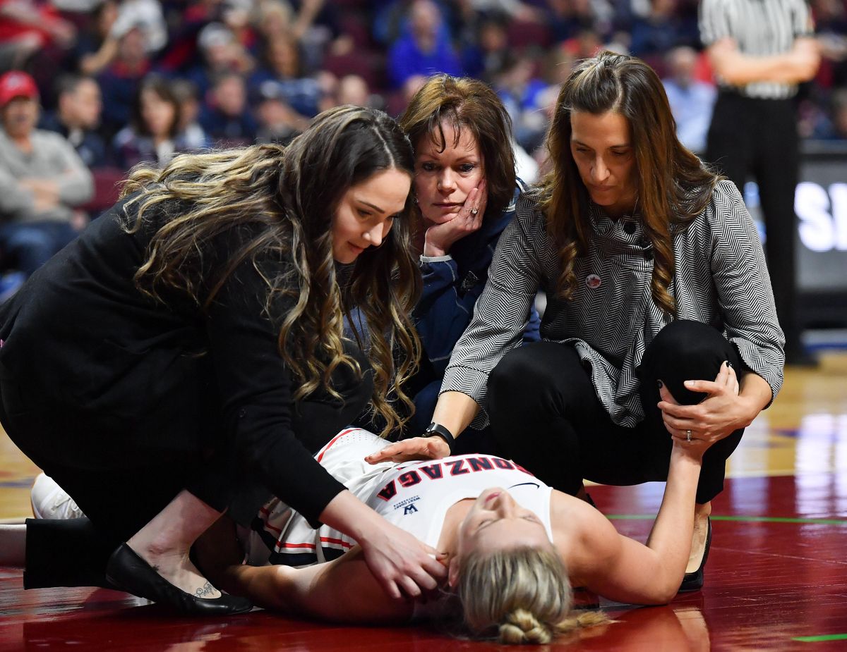 Gonzaga Bulldogs guard Laura Stockton (11) is comforted by Gonzaga Bulldogs head coach Lisa Fortier and staff after she took a fall and left the game with an injury during a WCC women