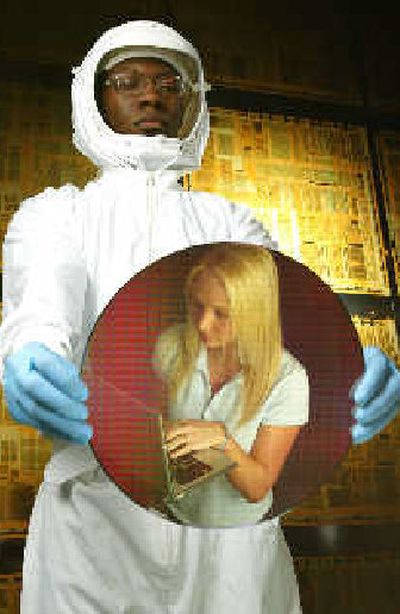 Intel technician Carlos Jones reflects the image of University of Oregon student Lydia Webb in a 12-inch wafer containing hundreds of microprocessors. Intel announced this week that it will build a $3 billion wafer fabrication facility in Chandler, Ariz., to manufacture next generation computer chips for desktop and laptop PCs in 2007.
(Feature Photo Service / The Spokesman-Review)