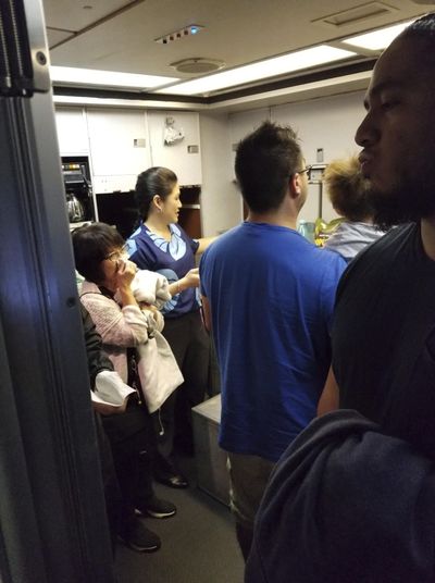 This Friday, Aug. 31, 2018, photo  shows people gathered in a back galley on a Hawaiian Airlines flight from Oakland, Calif., to Kahului, Hawaii, after a can of pepper spray went off inside the plane. (Nicholas Andrade / Courtesy photo)
