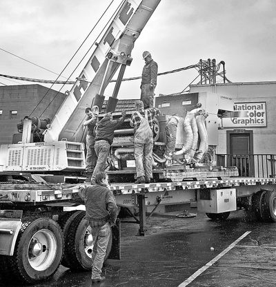 Workers with Hite Crane and Rigging prepare to lift a color press off a flatbed trailer and lower it into a new production area at National Color Graphics,  25 W. Boone Ave., in Spokane on Thursday.  (Christopher Anderson)