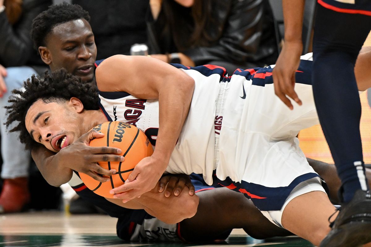 Gonzaga Bulldogs guard Ryan Nembhard (0) is wrapped up by Connecticut Huskies guard Hassan Diarra (10) late during the second half of of a college basketball game on Friday, Dec. 15, 2023, at Climate Pledge Arena in Seattle, Wash. The Connecticut Huskies won the game 76-63.  (Tyler Tjomsland/The Spokesman-Review)