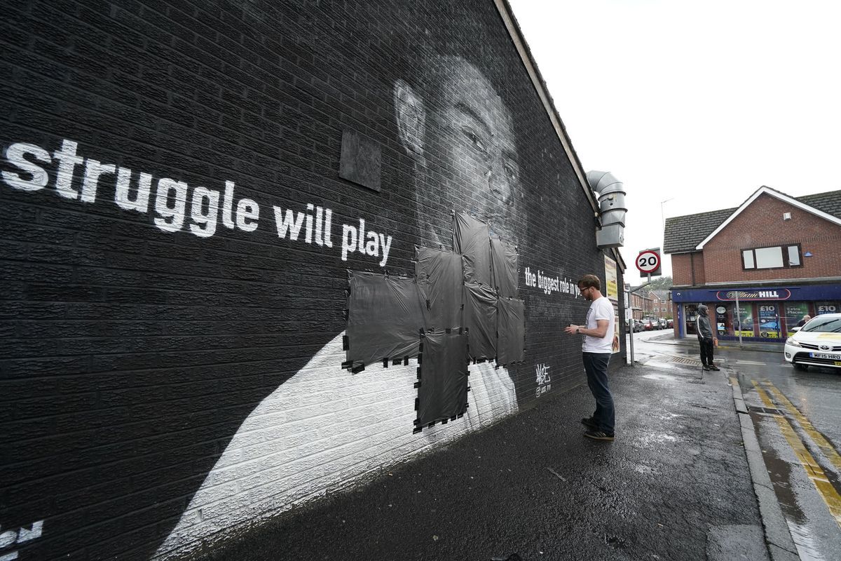 Ed Wellard, from Withington, tapes bin liners across offensive wording on the mural of Manchester United striker and England player Marcus Rashford on the wall of the Coffee House Cafe on Copson Street, which appeared vandalised the morning after the England soccer team lost the Euro 2021 final against Italy, in Withington, Manchester, England, Monday, July 12, 2021. British Prime Minister Boris Johnson has condemned the racist abuse directed at three Black England players who missed their penalties in the team’s shootout loss to Italy in the final of the European Championship on Sunday. Johnson tweeted that “those responsible for this appalling abuse should be ashamed of themselves.” Marcus Rashford’s penalty hit the post and spots kicks from Bukayo Saka and Jadon Sancho were saved by Italy