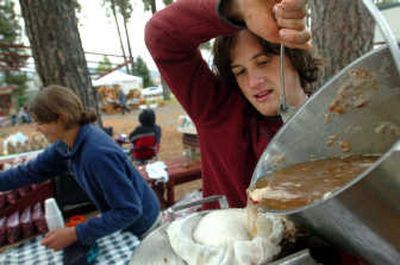 
Caleb Goss, right, strains freshly pressed apple cider through cheese cloth during the Kootenai County Farmers' Market on Saturday morning, . 
 (Jesse Tinsley / The Spokesman-Review)