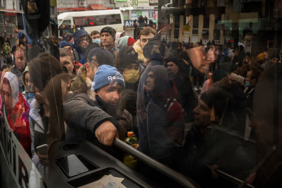 People try to get on a bus as they leave Kyiv, Ukraine, Thursday, Feb. 24, 2022. Russia launched a wide-ranging attack on Ukraine on Thursday, hitting cities and bases with airstrikes or shelling, as civilians piled into trains and cars to flee.  (Emilio Morenatti)