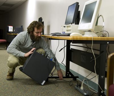 In the basement of St. Anne’s Children and Family Center, volunteer Ben Wadden helps set up and test donated computer equipment for this year’s Christmas Bureau. (Colin Mulvany)