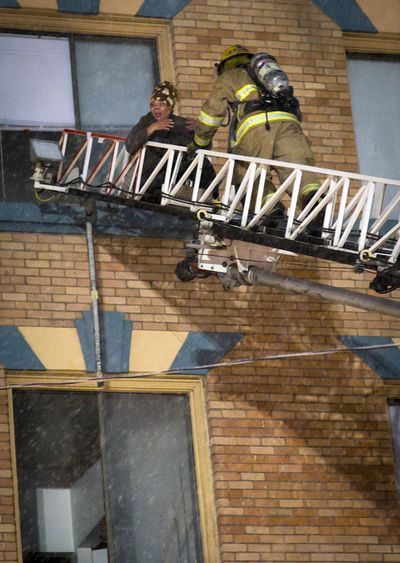 Eileen Epps is rescued from the fourth floor of the Sherwood Apartments by a Spokane  firefighter Wednesday evening at 123 N. Bernard St. “When I opened my door it was just black, billowing smoke,” said Epps.  (Colin Mulvany)