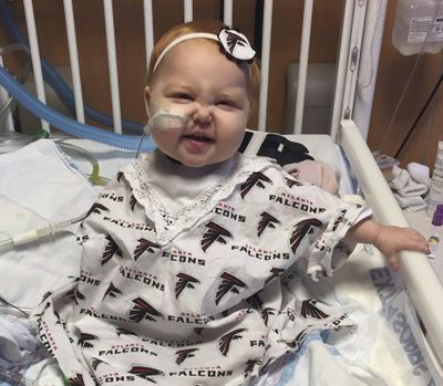 In this Jan. 22, 2017, photo provided by Children's Healthcare of Atlanta, 15-month-old Ella sits in a hospital bed at the Aflac Cancer Center of Childrens Healthcare of Atlanta in Atlanta. Children's Healthcare of Atlanta says the gown was made by the girl's grandmother to wear during the NFL's NFC Championship game between the Atlanta Falcons and the Green Bay Packers. The Falcons won 44-21. (AP)