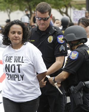 A protester is arrested by Phoenix police after she helped block an intersection to demonstrate against Arizona’s immigration law  Thursday.  (Associated Press)