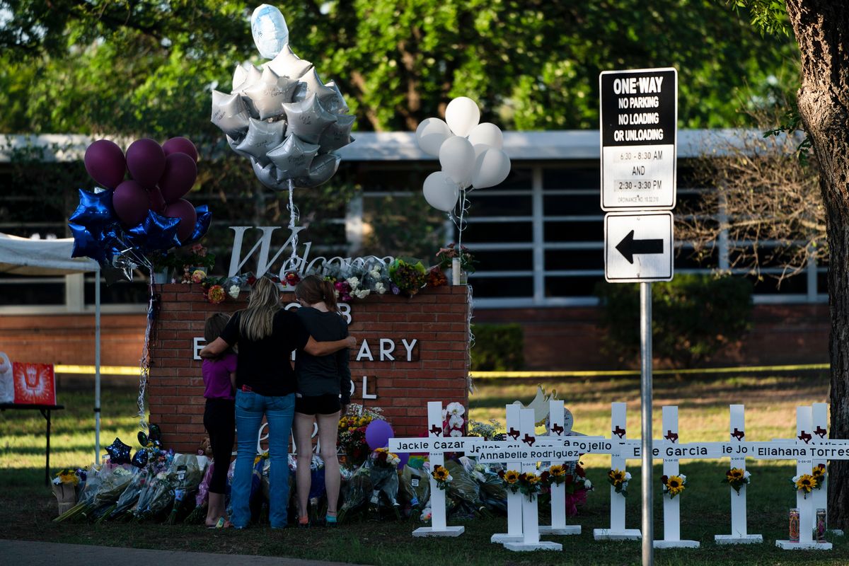 A family pays its respects next to crosses bearing the names of Tuesday’s shooting victims on Thursday at Robb Elementary School in Uvalde, Texas.  (Jae C. Hong)
