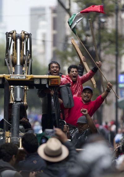 Protesting teachers arrive on a bulldozer Friday to prepare their barricades near the Zocalo square in Mexico City, where thousands have camped out for more than a month. (Associated Press)