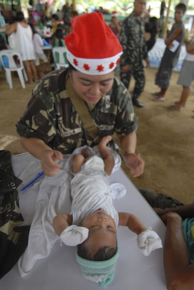 A Philippine army medic wearing a Santa hat prepares to examine a baby during a medical mission for flash flood victims at an evacuation center in Cagayan de Oro city, southern Philippines on Christmas day. Thousands of residents continue to be housed in evacuation centers after flash floods brought about by tropical storm Washi, that washed away their homes and killed more than a thousand people. The government disaster agency NDRRMC said more than a thousand others remain missing. (AP/Froilan Gallardo)