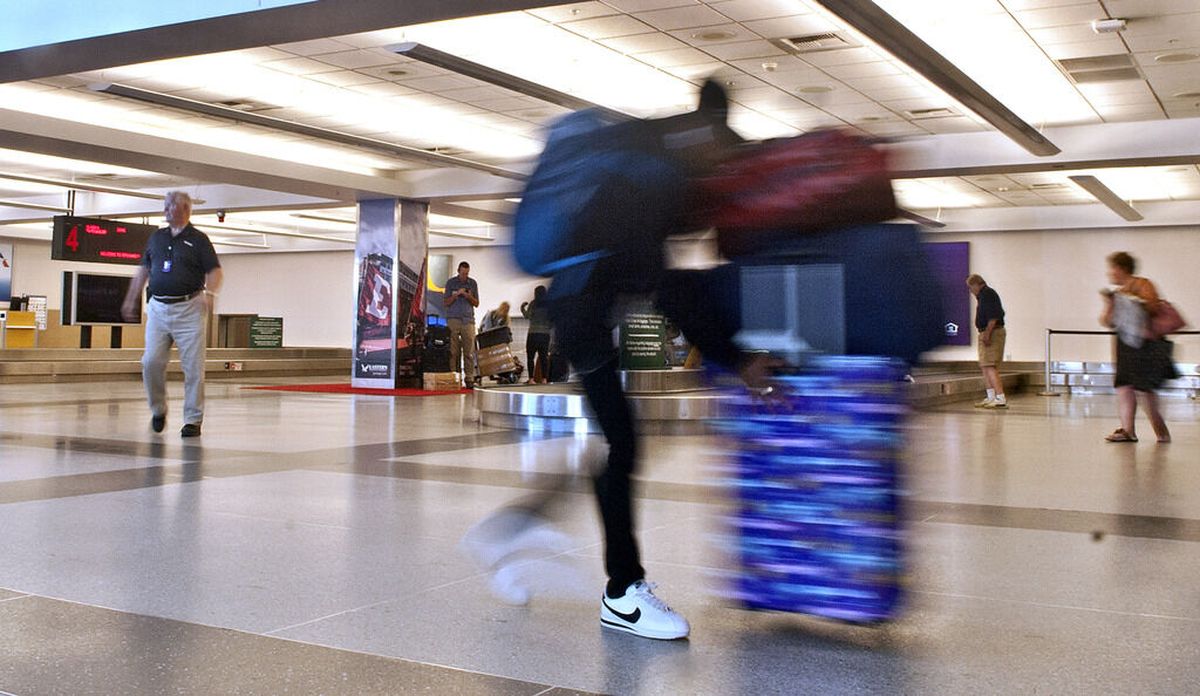 A passenger pushes their luggage through baggage claim at the Spokane International Airport on Tuesday, Aug. 20, 2019.  (Kathy Plonka / The Spokesman-Review)