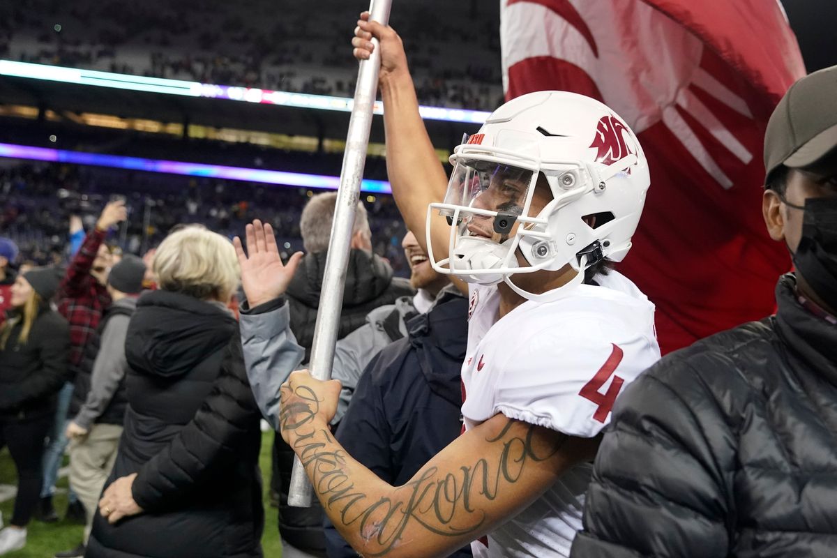 Washington State quarterback Jayden de Laura carries a Cougar flag on the field after WSU defeated Washington 40-13 in a Pac-12 game Friday, Nov. 26 in Seattle.  (Associated Press)