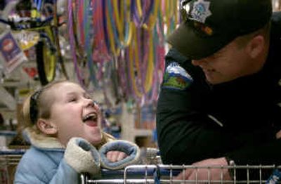 
Kayla Boyle, 7, of Post Falls, tells Rathdrum Police Officer Brian Williamson about her family at the Post Falls Wal-Mart Sunday while taking part in Holidays and Heroes. 
 (Tom Davenport/ / The Spokesman-Review)