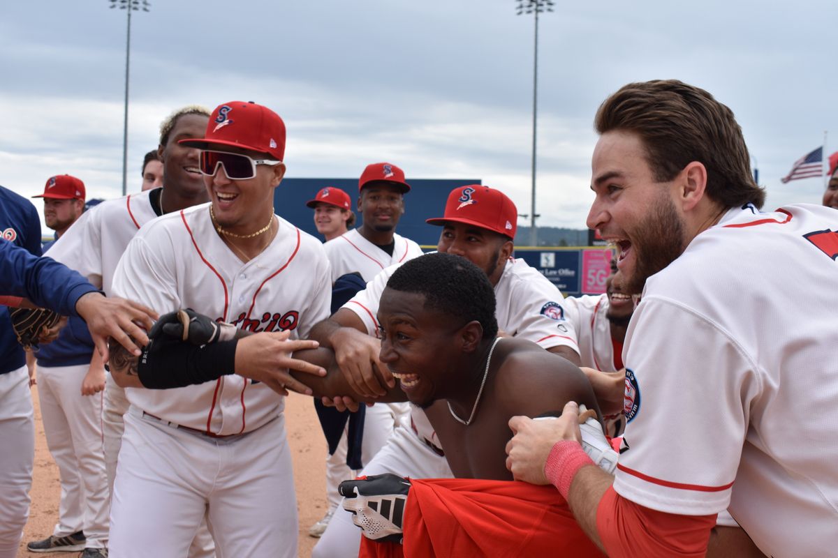 Spokane infielder Jean Perez, center, is mobbed by teammates after his 10th-inning bunt scored the winning run Tuesday at Avista Stadium.  (Spokane Indians/courtesy)