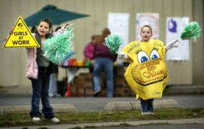 
Girl Scout Lexi Padilla, 10, left, shows Brownie Rayann McIntyre, 7, how to wave down passing cars to buy Girl Scout cookies on North Ash Saturday. 
 (Holly Pickett / The Spokesman-Review)