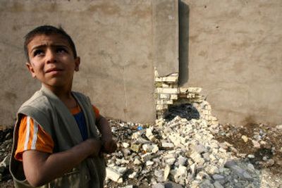 
An Iraqi boy stands next to a wall damaged by planted explosives in Baghdad, Iraq, on Wednesday. One police officer was hurt in the blast. 
 (Associated Press photo / The Spokesman-Review)