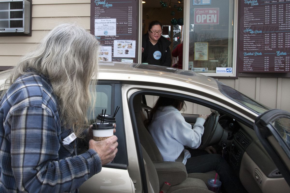 Diana Na serves up an order of coffee to Chris Christensen, left, and Marlene Humphrey at Na’s Coffee Break stand in Spokane Valley. “Don’t let them run you off,” says Humphrey. The stand was targeted with an attempted arson and a spray-painted racial slur in the parking lot. The discovery was made by Diana’s sister, Jenn, early Tuesday morning. The sisters are of Korean descent. (Dan Pelle)