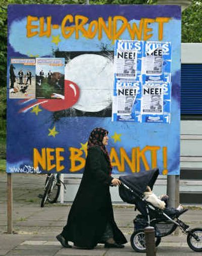 
A woman pushes a baby stroller past an election billboard reading 