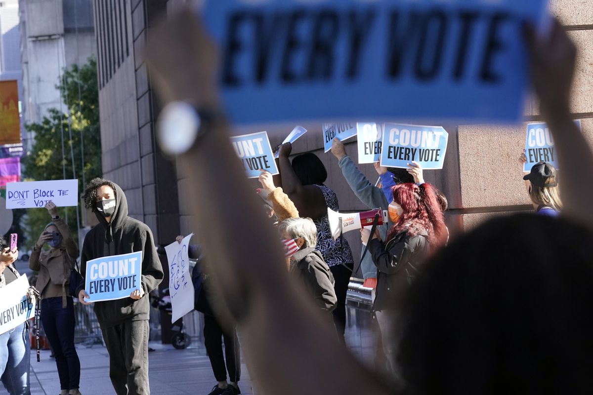 Demonstrators stand across the street from the federal courthouse in Houston, Monday, Nov. 2, 2020, before a hearing in federal court involving drive-thru ballots cast in Harris County. The lawsuit was brought by conservative Texas activists, who have railed against expanded voting access in Harris County, in an effort to invalidate nearly 127,000 votes in Houston because the ballots were cast at drive-thru polling centers established during the pandemic.  (David J. Phillip)