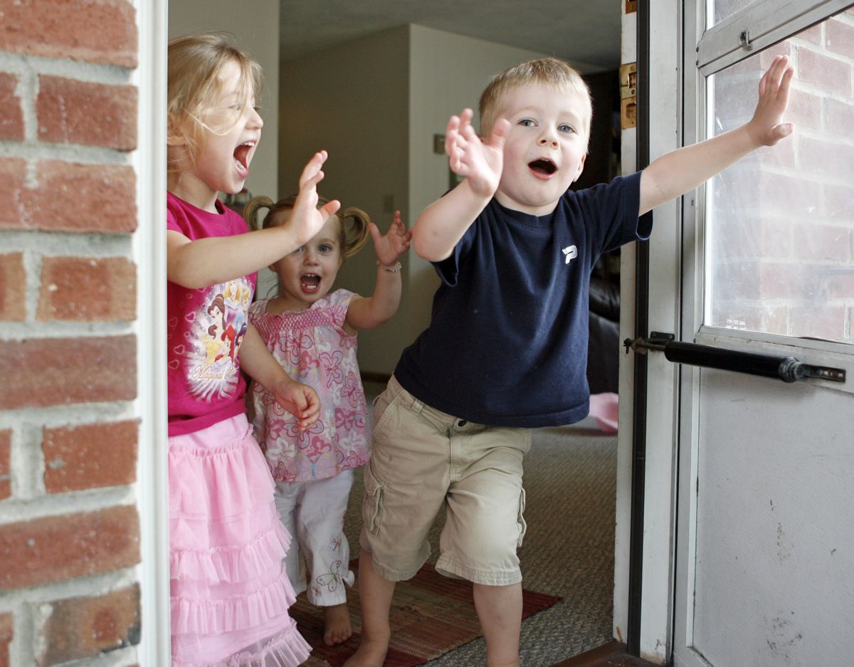 From left, Eva Evans, 3, Marian Pugh, 1, and Jack Pugh, 3, yell and wave out the door at the Pugh home in Watertown, Mass. (The Spokesman-Review)