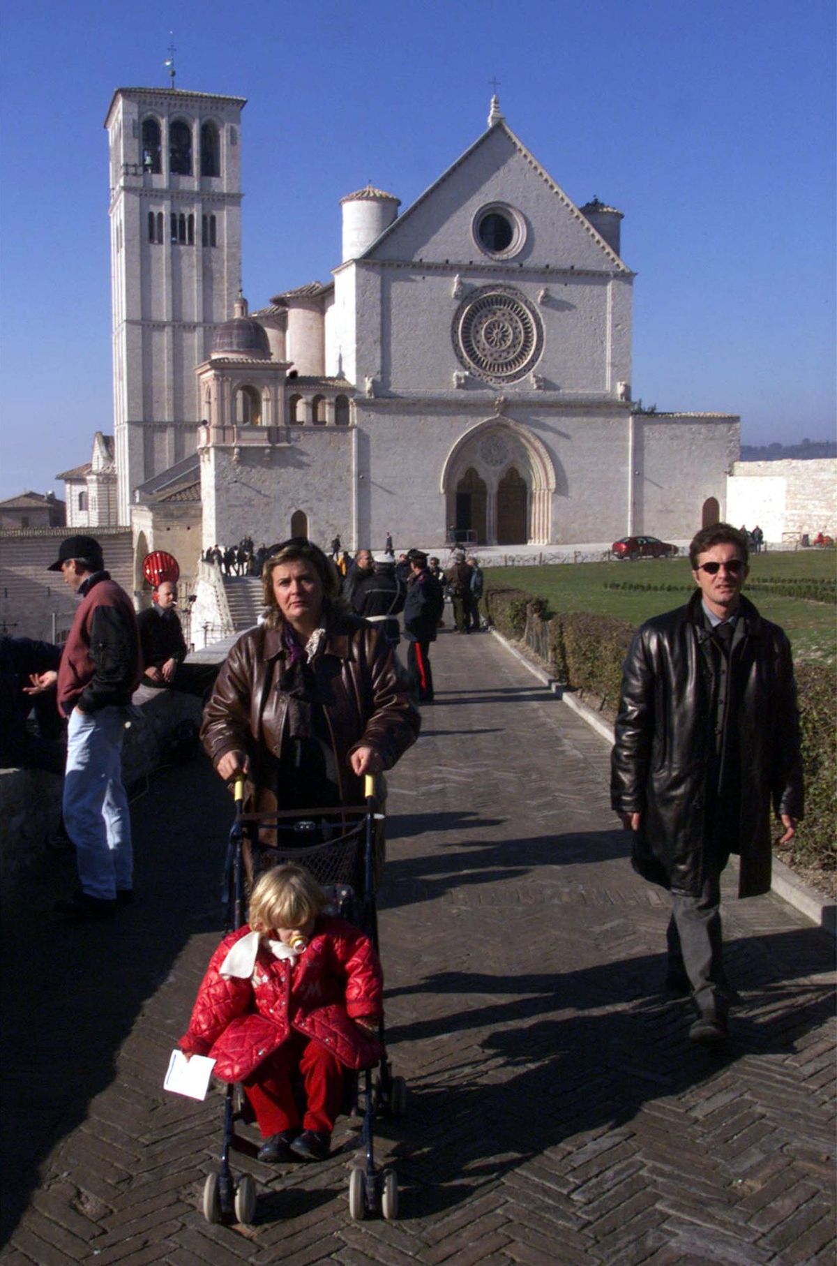 People walk on a sunny day in the area outside the Basilica of St. Francis of Assisi in this Nov.27, 1999 file photo. (PIER PAOLO CITO / AP)