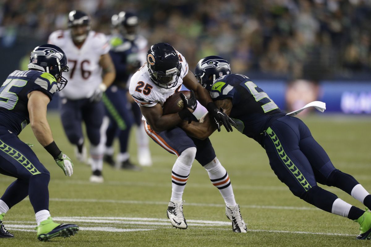 Chicago’s Ka’Deem Carey is dragged down by Seahawks’ Korey Toomer in the second half. (Associated Press)