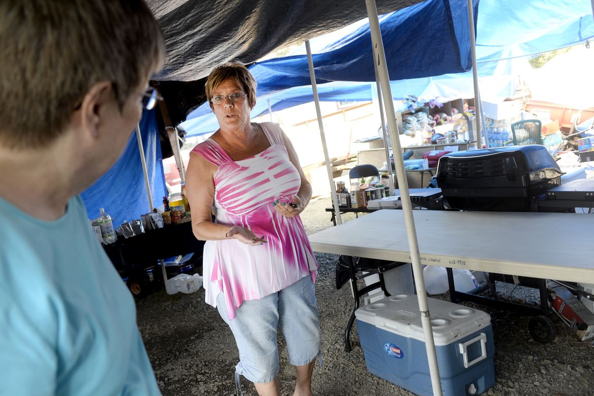 Sandi McCoin, center, manager of Riverside Village Mobile Home Park on Highway 2 north of Spokane, stands in the makeshift outdoor kitchen where cleanup workers and hard-hit residents have shared meals since a windstorm brought trees down on several homes July 23.