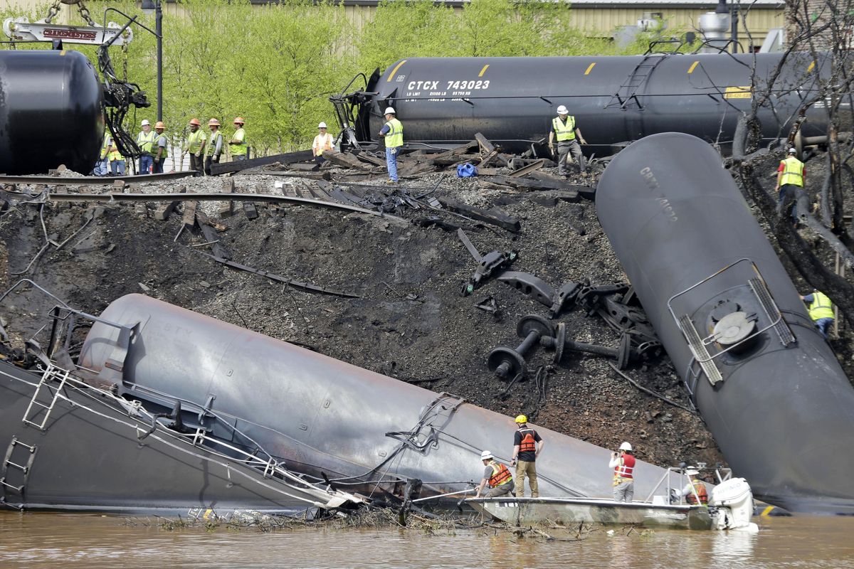 In this May 1, 2014, file photo survey crews in boats look over tanker cars as workers remove damaged tanker cars along the tracks where several CSX tanker cars carrying crude oil derailed and caught fire along the James River near downtown Lynchburg, Va. (Steve Helber / Associated Press)