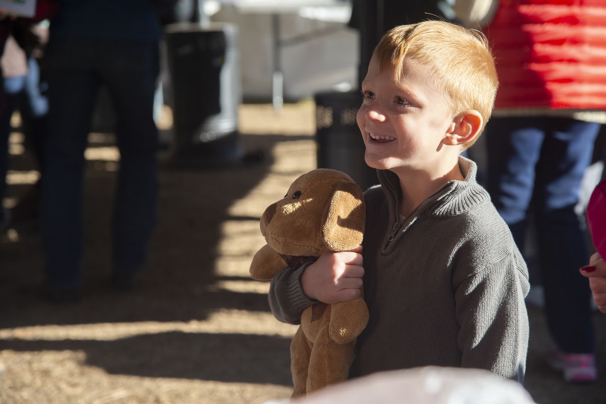 Kasen Adams, 6, smiles after picking a stuffed animal from a table of donations at a tent in Malden City Park, Wednesday, Dec. 2, 2020. The small Whitman County town destroyed by fire on Labor Day of this year is still struggling to get recovery and rebuilding efforts underway and families are still struggling to get basic needs met. On Wednesday, Kasen and his family came to a tent in the city park for a free lunch sponsored by the Episcopal Diocese of Spokane. Others had donated colorful Christmas quilts, stuffed animals and warm clothing.  (Jesse Tinsley/The Spokesman-Review)